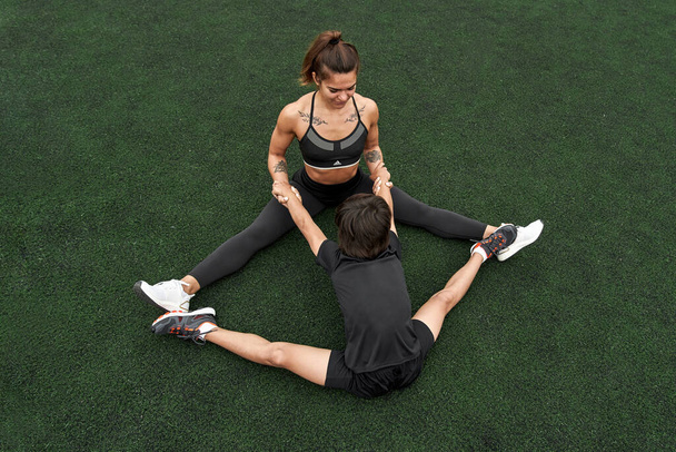 Mother teaching son stretching on athletic field - Foto, Imagem