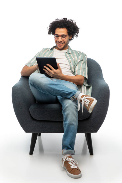 smiling young man with tablet pc sitting in chair - Foto, Imagem