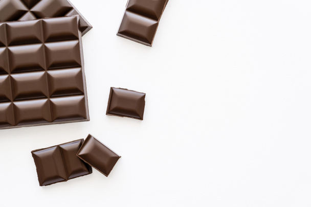 Top view of pieces and bars of chocolate on white background  - Fotografie, Obrázek