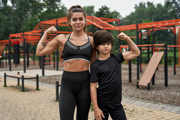 Serious athletic mother and son showing biceps - Фото, зображення