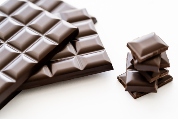 Close up view of bars and pieces of dark chocolate on white background  - 写真・画像