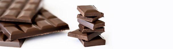 Close up view of chocolate pieces near blurred bars on white background, banner  - Photo, Image