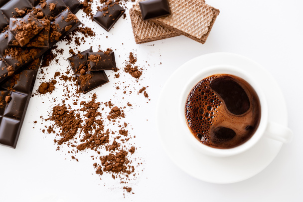 Vista superior del café en taza, gofres y chocolate negro sobre fondo blanco  - Foto, Imagen