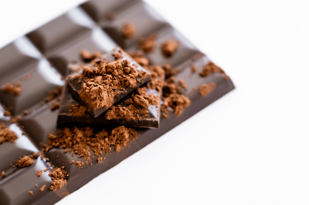 Close up view of cocoa powder on blurred chocolate on white background with copy space  - Fotó, kép
