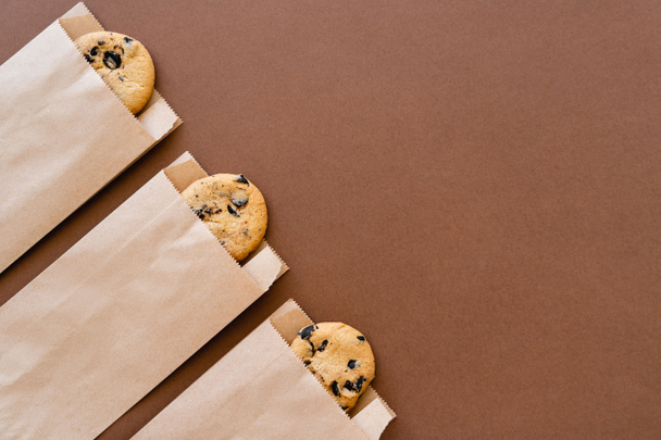 Vista superior de las cookies en paquetes de artesanía sobre fondo marrón con espacio de copia - Foto, imagen