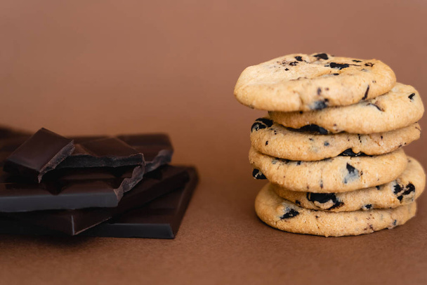 Close up view of cookies and dark chocolate bars on brown background  - Fotó, kép