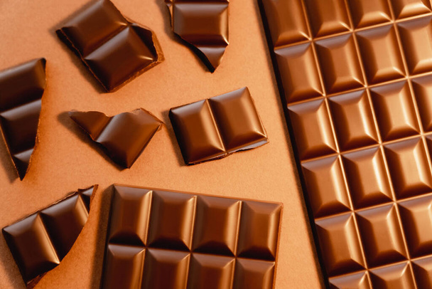 Top view of natural milk chocolate on brown background  - Fotografie, Obrázek