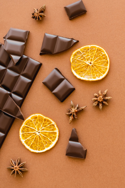 Top view of dry orange slice, chocolate and anise on brown background  - Fotografie, Obrázek