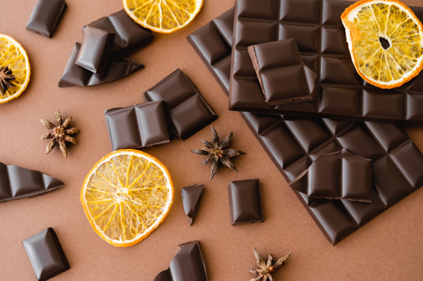Top view of dry orange slice, anise and chocolate on brown background  - Foto, immagini