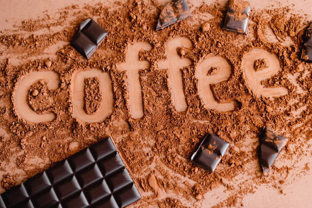 Top view of coffee lettering in cocoa and chocolate on brown background  - Photo, Image