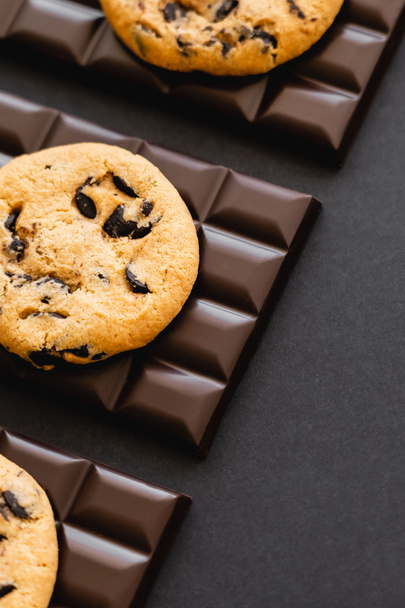 Top view of delicious cookies on dark chocolate on black surface  - Fotó, kép