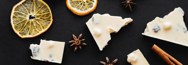 Top view of dry orange slices, spices and white chocolate on black background, banner  - Fotó, kép