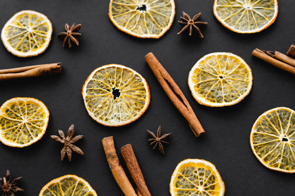 Top view of dry orange slices, cinnamon and anise on black background  - Foto, Imagem