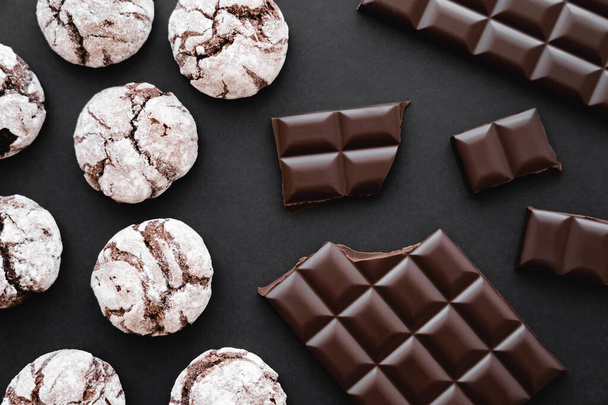 Vista superior de galletas con azúcar en polvo y chocolate sobre fondo negro  - Foto, Imagen