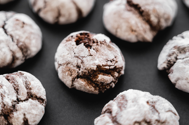 Close up view of baked biscuits with powdered sugar on black surface  - Foto, Imagen