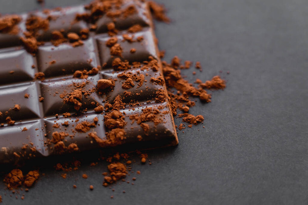 Close up view of cocoa powder on chocolate on black background  - Valokuva, kuva