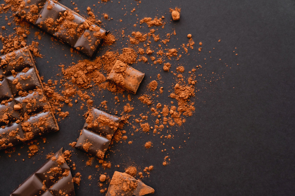 Top kilátás természetes kakaópor és csokoládé fekete alapon  - Fotó, kép