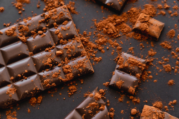 Top view of dark chocolate and coca powder on black background  - Zdjęcie, obraz