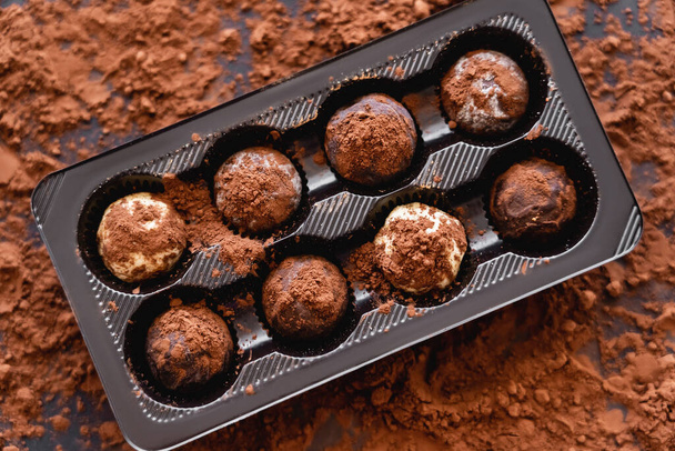 Vista superior de caramelos y cacao seco desenfocado sobre fondo negro  - Foto, Imagen
