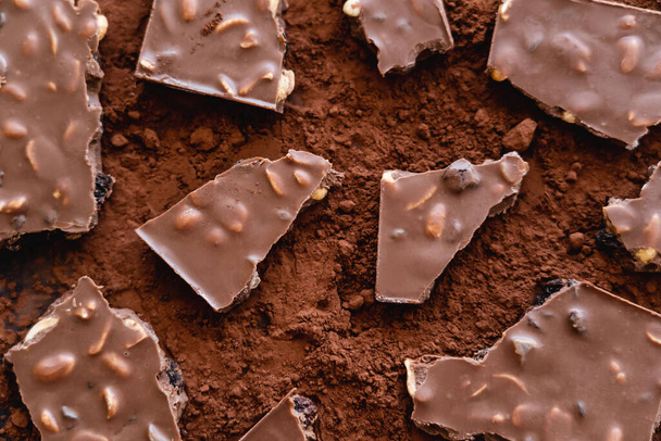 Top view of chocolate with nuts on cocoa powder - Zdjęcie, obraz