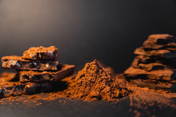 Close up view of dry cocoa and blurred chocolate on black background  - Valokuva, kuva