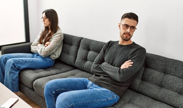 Молодая латиноамериканская пара злится, сидя дома на диване в тишине. - Фото, изображение