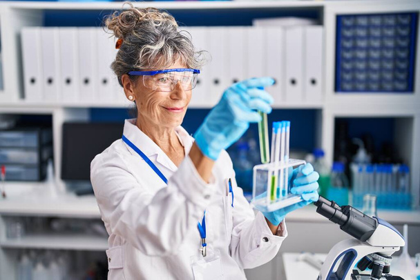 Mulher de meia idade cientista segurando tubos de ensaio em laboratório - Foto, Imagem