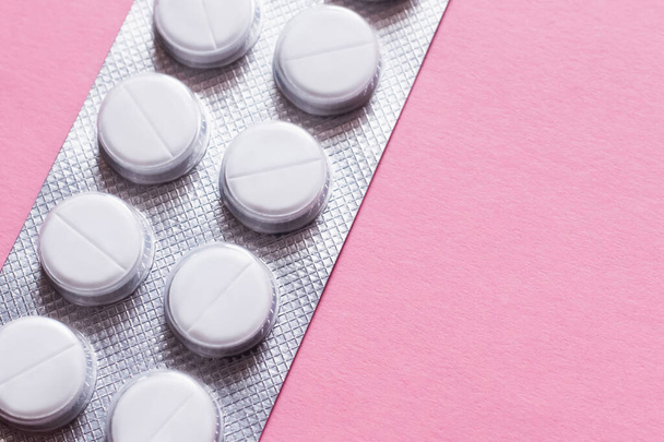 close up view of blister pack with white round shape pills isolated on pink - Foto, afbeelding