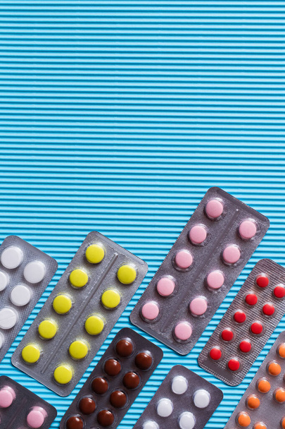 horní pohled na blistry balení s různými pilulky na modrém texturovaném pozadí - Fotografie, Obrázek