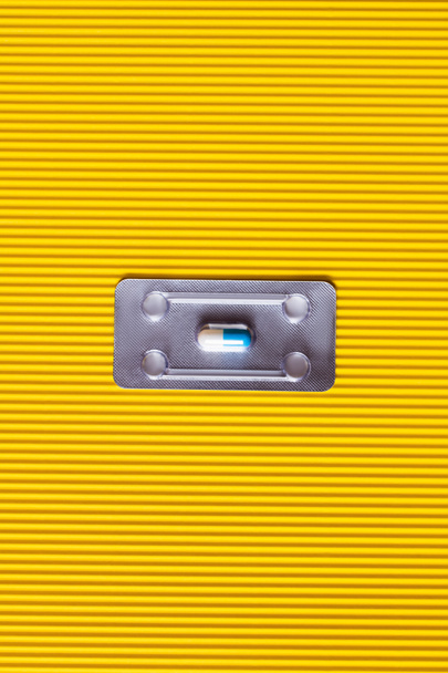bovenaanzicht van blisterverpakking met antibiotica capsule op getextureerde gele achtergrond - Foto, afbeelding