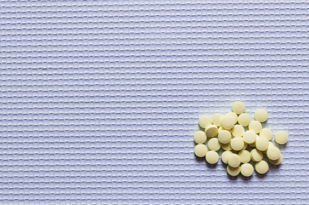 vue de dessus de pile avec des pilules de forme ronde jaune sur fond texturé blanc - Photo, image