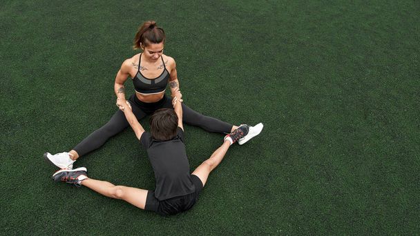 Slim mother and son stretching on athletic field - 写真・画像