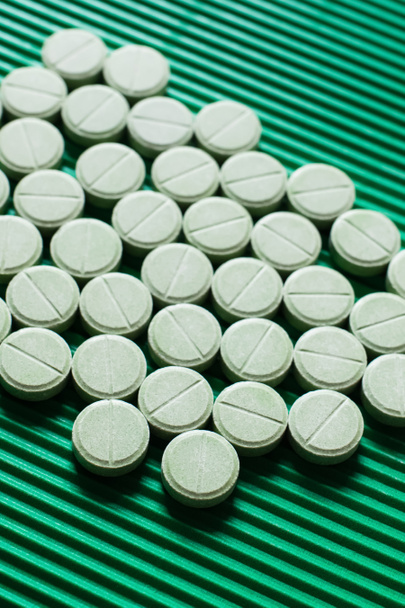 vista de cerca de la medicación de forma redonda sobre fondo verde texturizado - Foto, Imagen