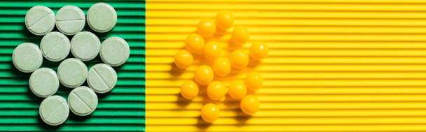 丸みを帯びた形状の丸薬とビタミンの上から見た緑と黄色の背景バナー - 写真・画像