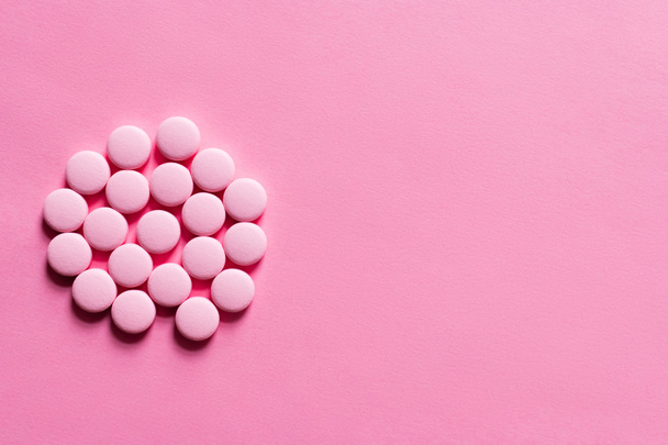 top view of pile with pills in round shape on pink background - Фото, изображение