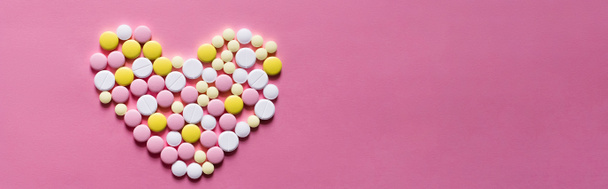 flat lay view of different round pills in shape of heart on pink background, banner - Foto, afbeelding