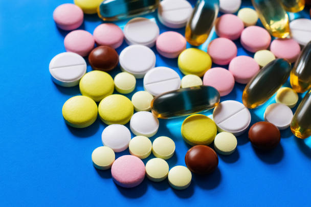 close up view of different colorful pills and capsules on bright blue background - Foto, afbeelding