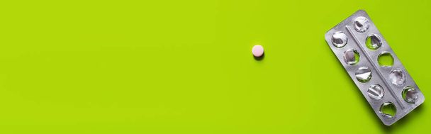 top view of used blister pack near round shape pill on green background, banner - Foto, afbeelding