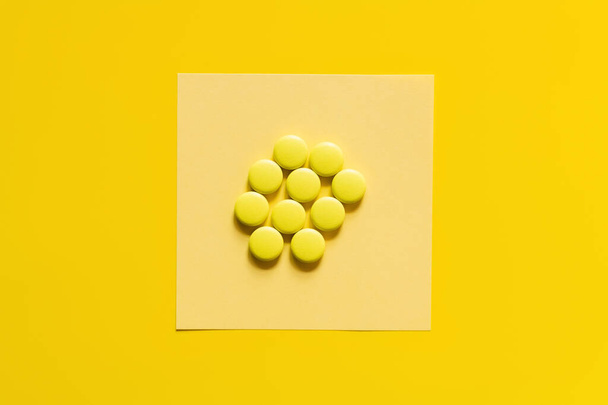 top view of round shape pills on paper note on yellow - Foto, Bild