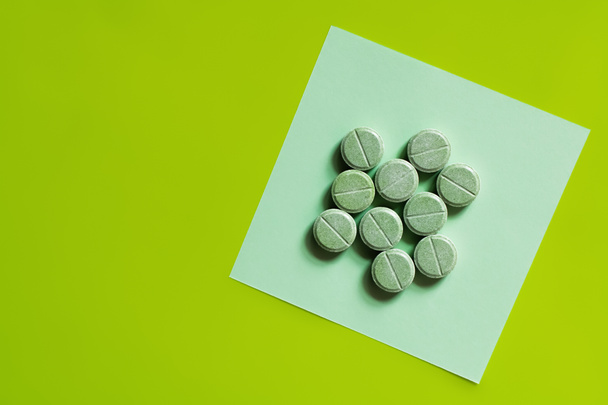 vrchní pohled na kulatý tvar pilulky na papíře poznámka na zelené - Fotografie, Obrázek