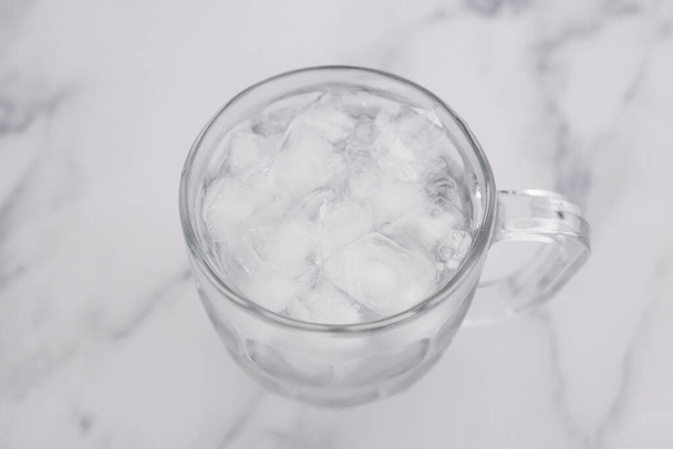 pint glass with tap water and ice cubes over marble background, concept of drinking enough water or sobriety - Фото, зображення