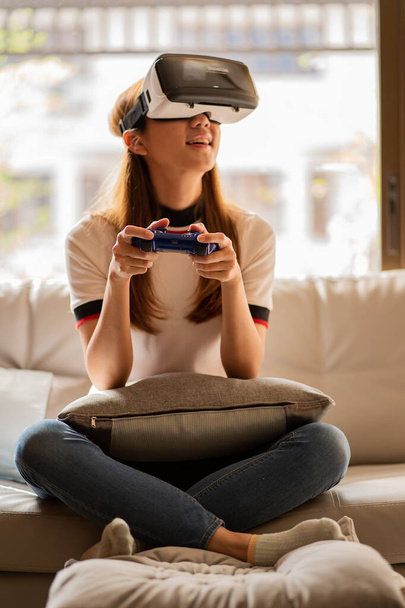 Cheerful Caucasian woman wearing VR glasses at home Girl having fun with glasses with hands making imaginary gestures on the device. - Фото, зображення