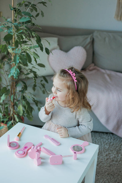 Cute little girl is playing in a beauty salon. Beautiful girl of 3 years old makes makeup with children's cosmetics at home. Spring. - Fotoğraf, Görsel
