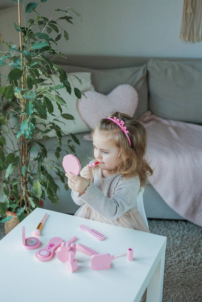 Cute little girl is playing in a beauty salon. Beautiful girl of 3 years old makes makeup with children's cosmetics at home. Spring. - Fotoğraf, Görsel