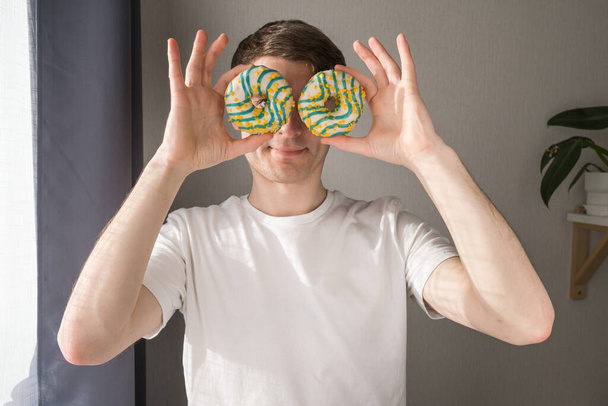 Man holding donuts in front of his face. - Fotó, kép