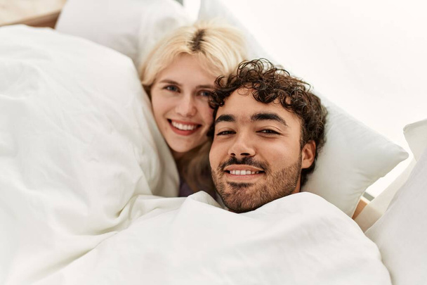 Jeune beau couple couché au lit et recouvert d'une couverture à la maison. - Photo, image