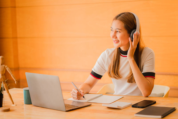 Teenage Asian students wearing headphones are communicating via video conferencing for online learning. In app video conferencing work at home concept - 写真・画像