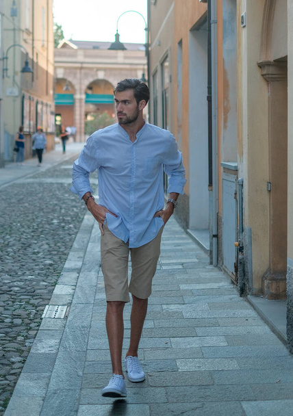 handsome Italian dark-haired boy walks downtown in bermuda. High quality photo - Photo, Image