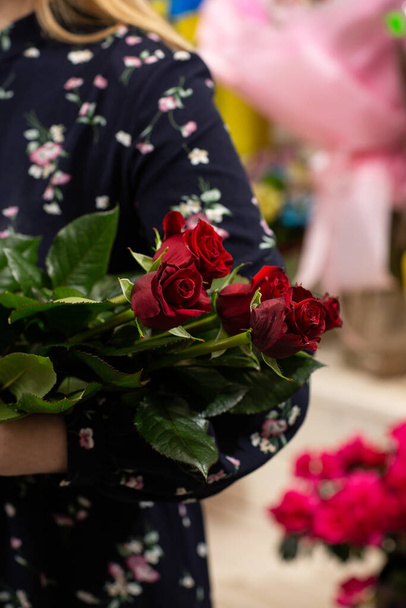 Μπουκέτο με κόκκινα τριαντάφυλλα. Ιδέα για δώρο για την ημέρα του Αγίου Βαλεντίνου. Ανθοπωλείο γυναίκα κρατώντας ένα φρέσκο μπουκέτο - Φωτογραφία, εικόνα