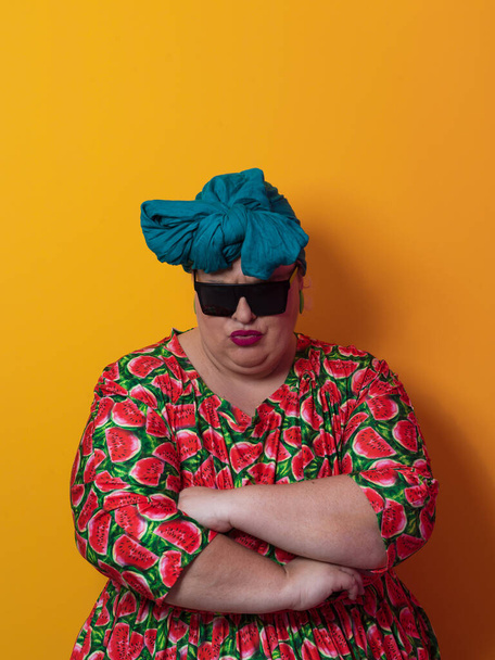 Funny plus size sexy model woman with trendy sunglasses, fashionable overweight blonde in colorful dress posing at the yellow background in studio. - Valokuva, kuva